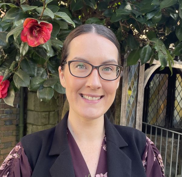 emma heeran 3 Head and shoulders photograph of Emma Heeran standing in front of the college entrance