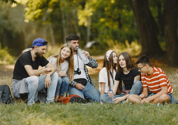 A group of young people sitting in a park chatting and smiling