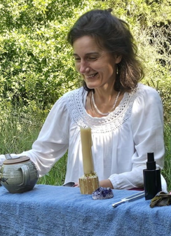 Emily Thomas sitting at a table smiling wearing a white shirt