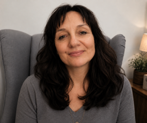 A white woman with long dark hair smiling facing the camera